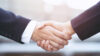 close-up of two persons shaking hands, only the hands and a part of the arms visible; Nahaufnahme zweier Hände, die sich schütteln